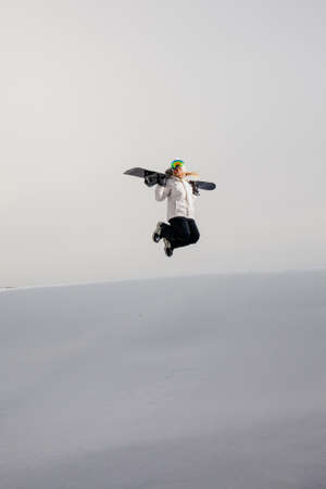 Young woman jumping with her snowboardの写真素材