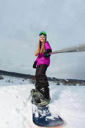 Young woman with the snowboard shooting a selfie by her action cameraの写真素材