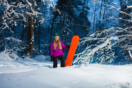 Young sexy woman with her snowboard in the dark winter forestの写真素材