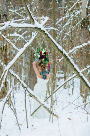 Portrait of the bride in the cold winter forest with a beautiful bridal bouquetの写真素材