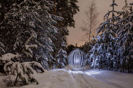 Futuristic glowing sphere near the tree at the background of winter night landscapeの写真素材