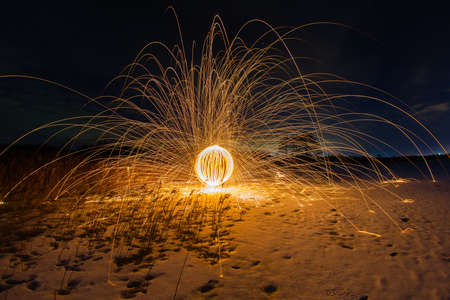 Trajectories of burning sparks on the surface of frozen lake at the background of spring night landscapeの写真素材