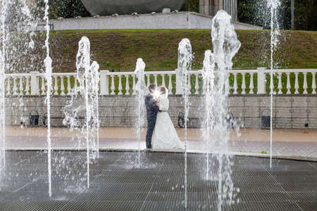Groom and bride next to a fountain and high water jetsの写真素材