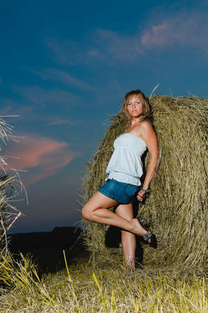 Young sexy blonde posing near a haystack