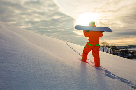 Snowboarder climbing on the top of ski slopeの写真素材