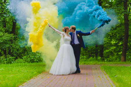 Bride and groom with colorful smoke bombsの写真素材