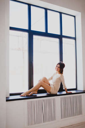 Tall slender brunette near the windowの写真素材