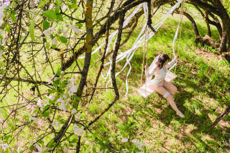 Young sexy bride sitting on a white swing in seductive poseの写真素材