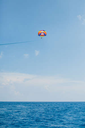 People flying on a colorful parachute towed by a motor boat