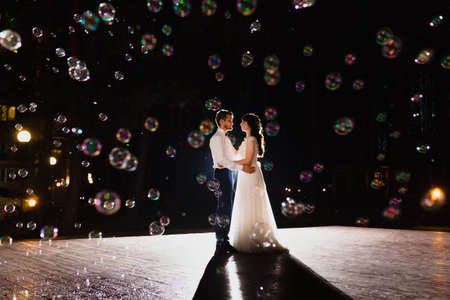 Couple of newlyweds and huge amount of bubbles are flying in the air