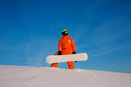 Snowboarder freerider with white snowboard standing on the top of the ski slopeの写真素材