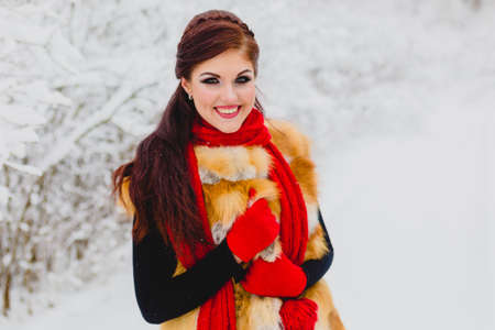 Pretty model with red hair posing in winter forestの写真素材