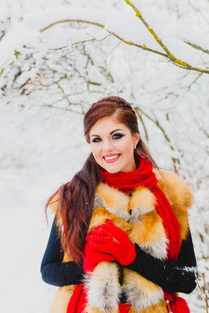 Pretty model with red hair posing in winter forestの写真素材