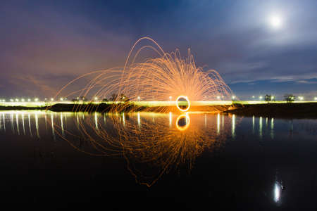 Trajectory of burning sparks reflected on the river surface