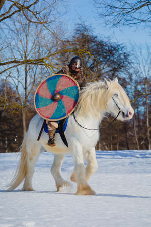 Man in suit of ancient warrior riding big white horseの写真素材