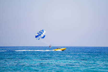 Couple of tourists flies on a blue and white parachuteの写真素材