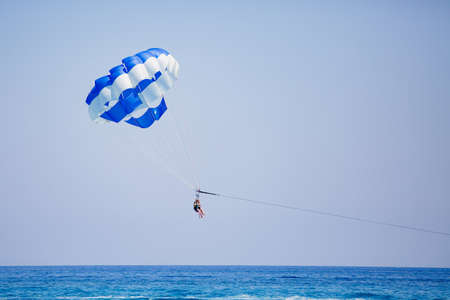 Couple of tourists flies on a blue and white parachuteの写真素材