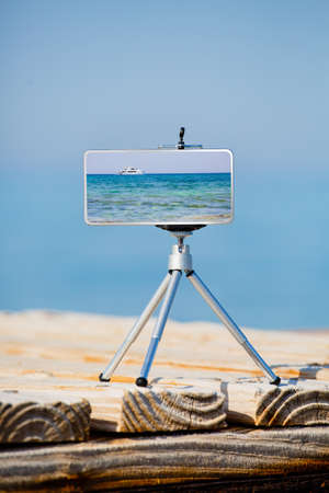 Smartphone on tripod making photo and video of sea landscapeの写真素材