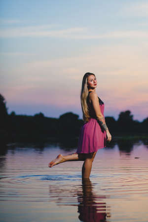 Beautiful blond model with long hair standing in the waterの写真素材