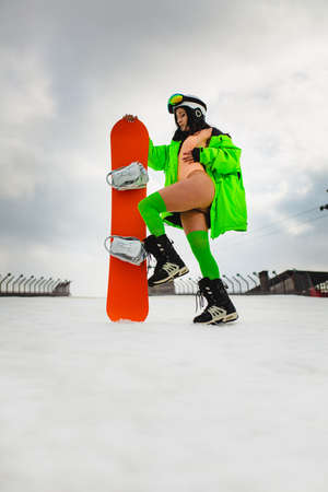 Young beautiful woman posing with a snowboard on a ski slopeの写真素材