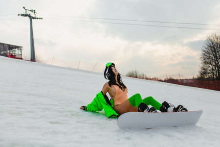 Young beautiful woman posing with a snowboard on a ski slopeの写真素材