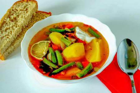 vegetable stew in a plate standing on the table next to two pieces of breadの写真素材