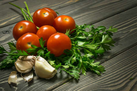 tomatoes, parsley and garlic are on an old tableの写真素材
