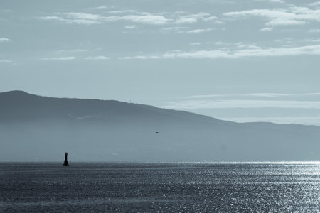 morning at sea, lighthouse and mountains in the hazeの写真素材