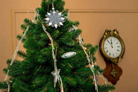 Christmas and New Year tree and a clock on a brown wall. Idea for holiday like Christmas and New year, for covers books, magazines, articles.の写真素材