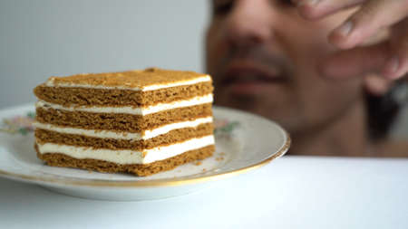 man sweet tooth hunting for a piece of cake on a plate he hiding than sneak up to his passion unhealthy food, stretching his hand, almost take it, gluttony, bad habit, endorphins, forbidden fruitの写真素材