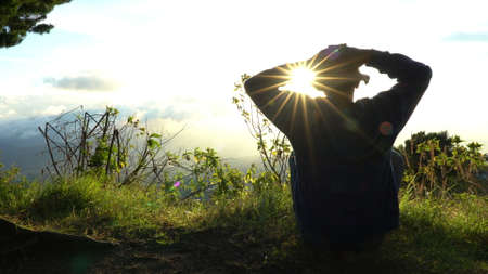 Man hermit meeting up sun rise on the edge of mountains. Doing meditation in sun light.の写真素材