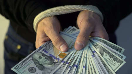 male hand bound with the rope holding pile of money american dollar bank notes, financial rectrictions conceptの写真素材