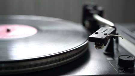 The vinyl record on DJ turntable record player close up. The rotating plate and stylus with the needle close-up neutral colorの写真素材