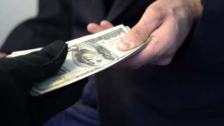business man giving money to hand in black gloves, crime concept bribeの写真素材