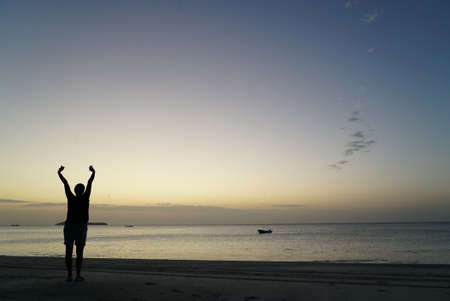 Lonely human silhuette on the sea cost looking at sunset above a water. Solitary, silence and reclusion conceptの写真素材