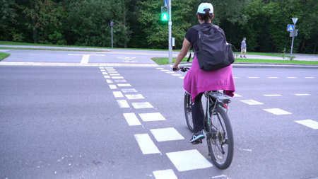 Woman cyclist, female riding bicycle on street crossing without helmet, pedestrian cycling, bicycle...