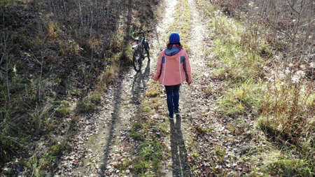 Cyclist Woman Riding On Bicycle On Countryside Road in autun forest, Having Fun And Enjoying Life. aerial shotの写真素材