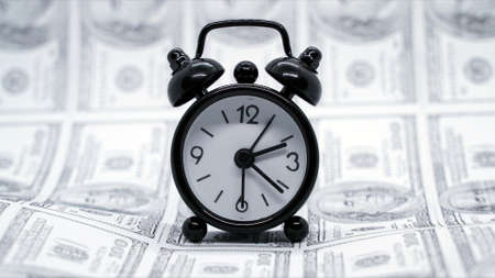 Business finance and money concept. Save money for prepare in the future. Clock passing with dollars money printed on background photoの写真素材