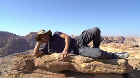 latin man rich out the peak of mountain and having a rest, happy adventure, man tourist trekking outdoor, travel conceptの写真素材
