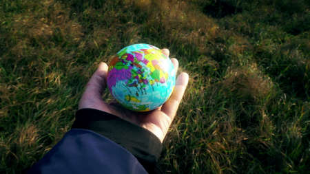 world in hand, female hand holding planet globe earth outside on grass background, human influence, ecological, climate change, catastrophe, disaster concept videoの写真素材