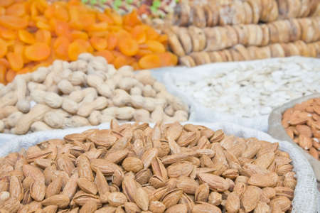 Natural unprocessed almonds in focus on foreground with unfocused nuts and dried fruit on backroundの写真素材
