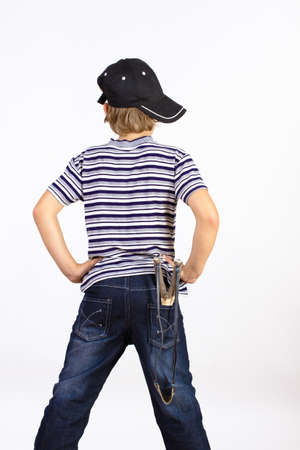 boy standing back with a slingshot in his pocketの写真素材