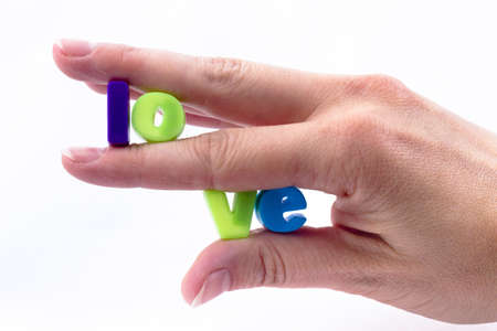 Inscription love patchwork of letters held between the fingers of blue and green in colorの写真素材