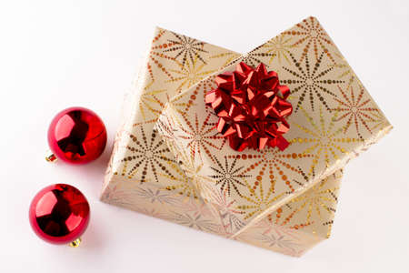 Two Christmas presents wrapped in wrapping paper with a golden pattern with red rosette and flasks