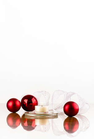 Christmas decoration of red flask white ribbon and a candle on a glossy surfaceの写真素材