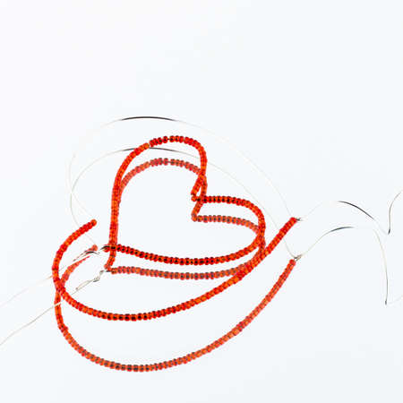bead heart formed of wire and red beads on the mirrorの写真素材