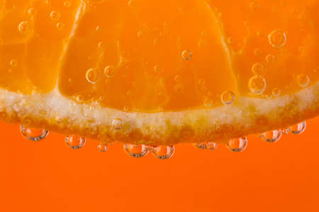 thin slice of tangerine bubbles in mineral drinks on the orange backgroundの写真素材