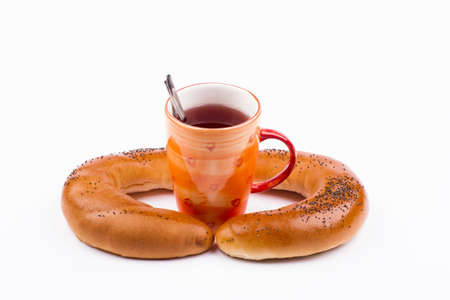cooked until golden sweet buns sprinkled with poppy seeds with a cup of tea on a white backgroundの写真素材