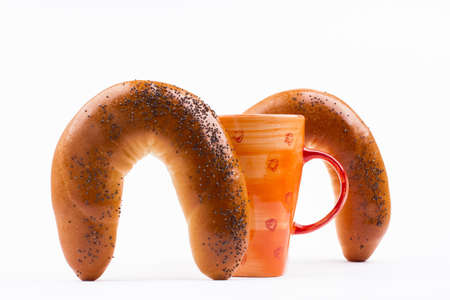 cooked until golden sweet buns sprinkled with poppy seeds with a cup of tea on a white backgroundの写真素材
