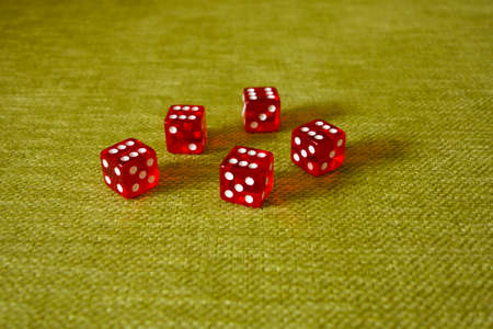 Five dice on a green cloth background with a drop of sixes